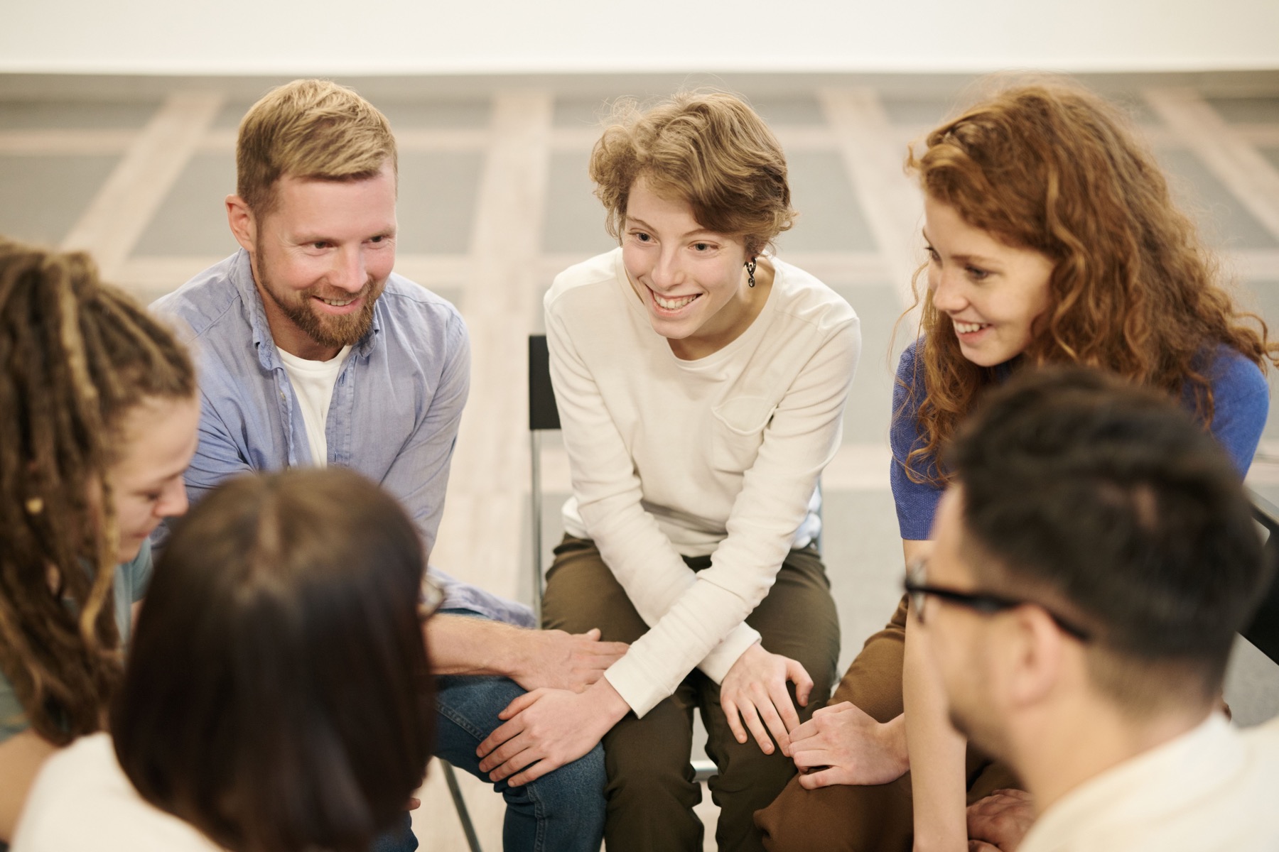 Adults seated in a circle with their hands joined in support